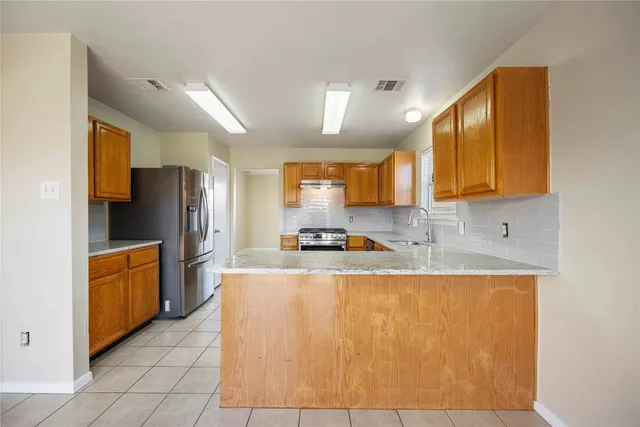 a large kitchen with stainless steel appliances granite countertop a refrigerator a stove top oven and a sink