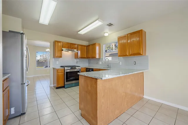 a kitchen with stainless steel appliances granite countertop a stove a sink and a refrigerator