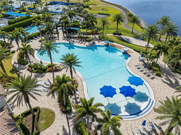 a view of a swimming pool with lawn chairs potted plants
