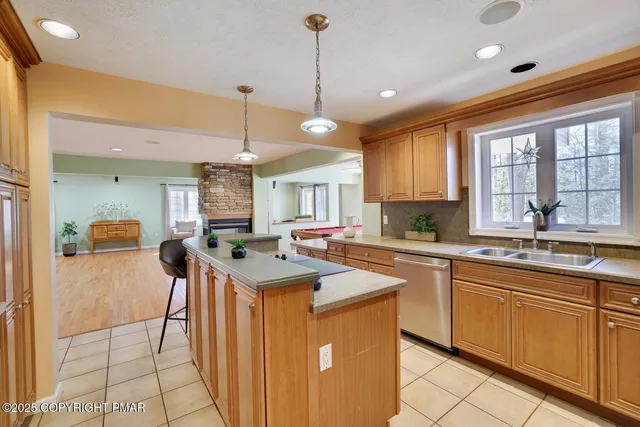 a kitchen with stainless steel appliances granite countertop a sink a stove a refrigerator and island with wooden floor