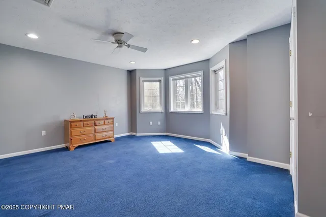 an empty room with windows and ceiling fan
