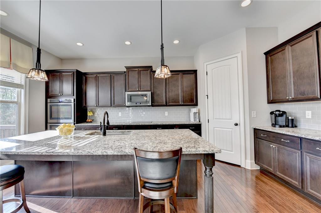 5930 Caveat Court Suwanee, GA 30024 - Photo 28 of 98 a kitchen with kitchen island granite countertop a table and chairs in it