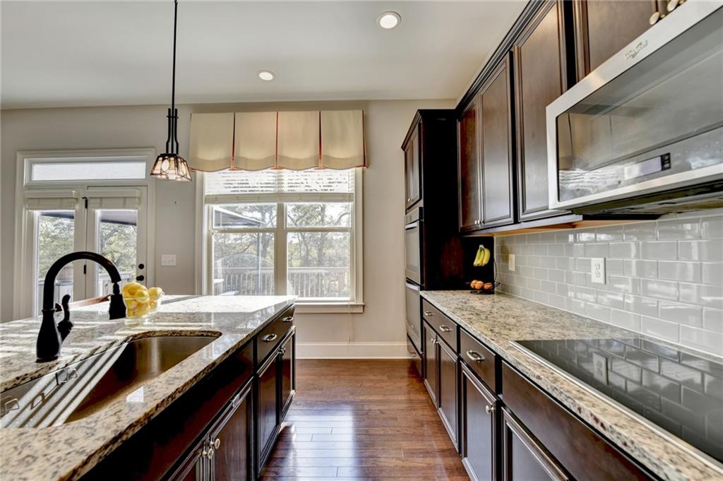 5930 Caveat Court Suwanee, GA 30024 - Photo 29 of 98 a kitchen with stainless steel appliances granite countertop a sink a stove and a wooden floors