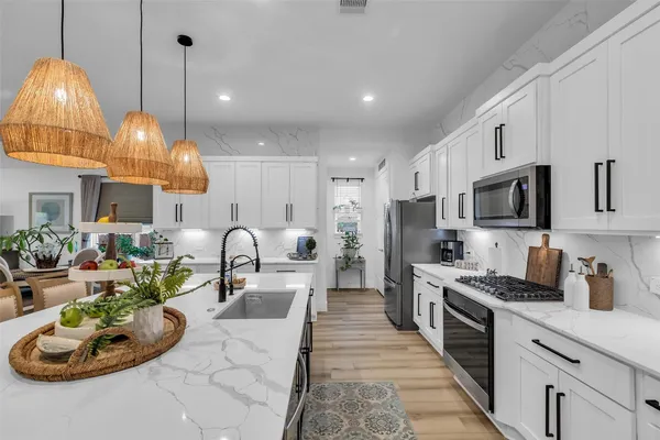 a kitchen with stainless steel appliances granite countertop a stove a sink dishwasher a dining table and chairs with wooden floor