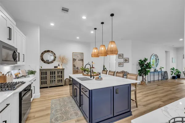 a kitchen with stainless steel appliances kitchen island granite countertop a table chairs sink and cabinets