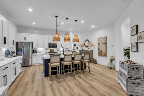 a kitchen with stainless steel appliances kitchen island granite countertop a dining table chairs and white cabinets