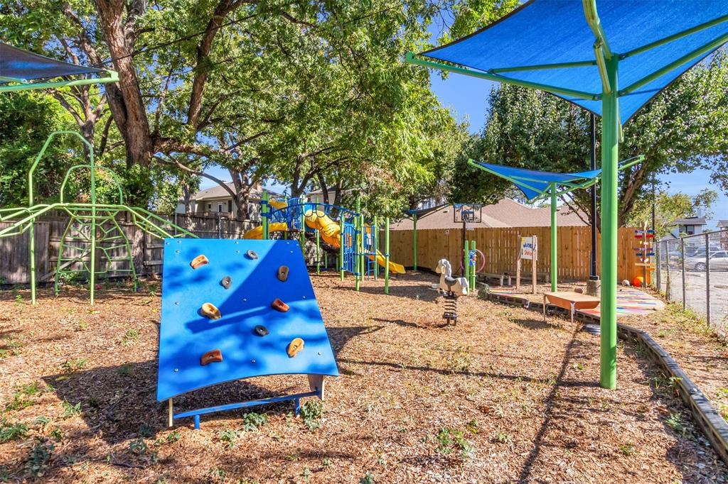 4121 Junius Street, Unit B Dallas, TX 75246 - Photo 7 of 32 Dedicated play area featuring a blue climbing wall, multiple slides, a jungle gym, and a spring rider