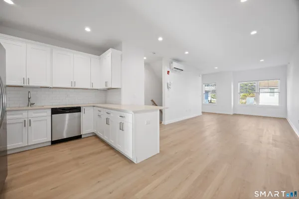 a large kitchen with stainless steel appliances granite countertop a stove a sink and white cabinets