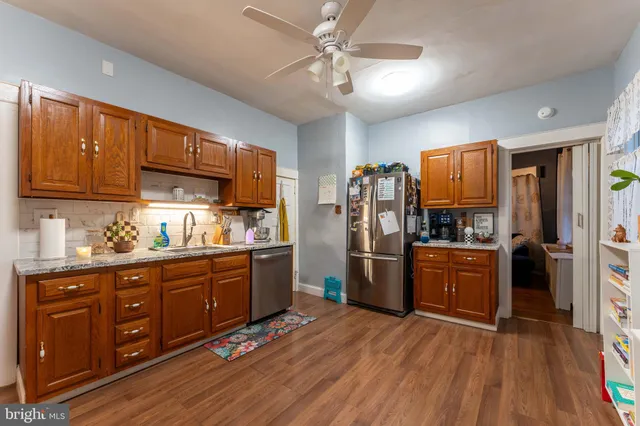 a kitchen with stainless steel appliances granite countertop a refrigerator oven a sink dishwasher and wooden cabinets with wooden floor