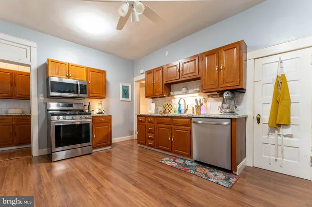 a kitchen with granite countertop wooden floors stainless steel appliances and a window