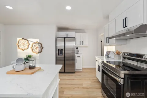 a kitchen with stainless steel appliances granite countertop a sink a stove and a refrigerator