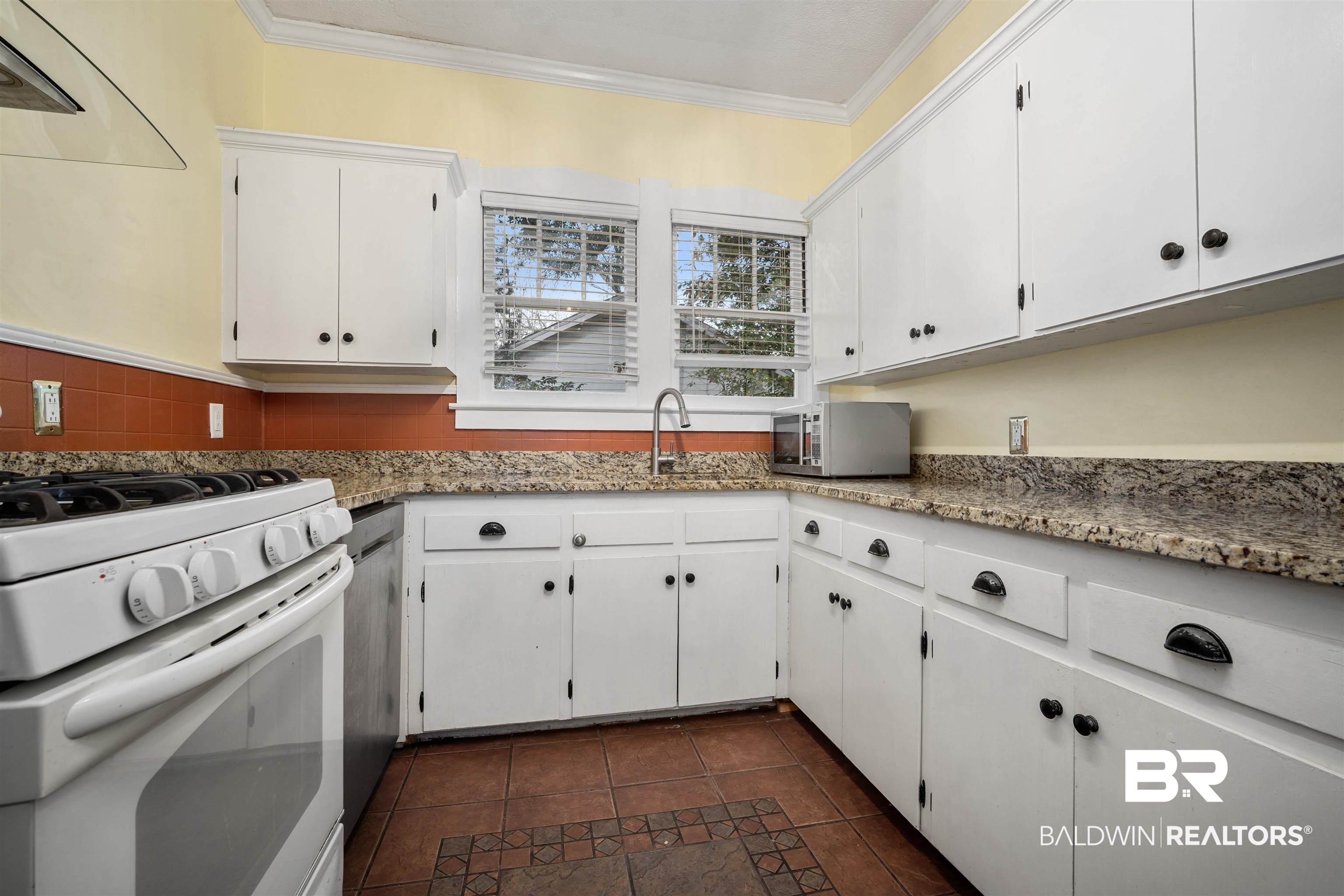 118 Mohawk Street Mobile, AL 36606 - Photo 6 of 26 Kitchen featuring gas range gas stove, exhaust hood, white cabinetry, stainless steel microwave, and light stone countertops