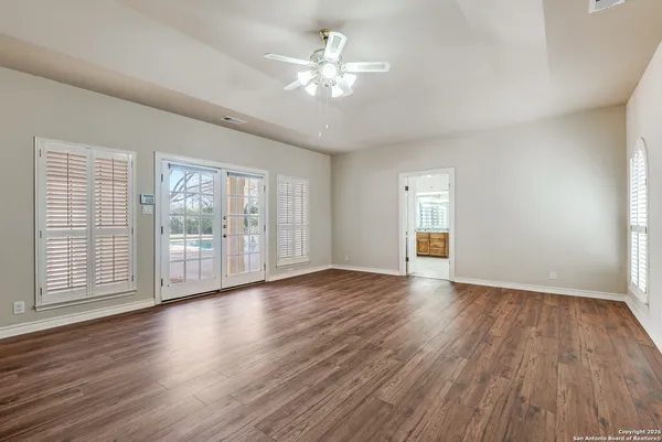 a view of an empty room with wooden floor and a window