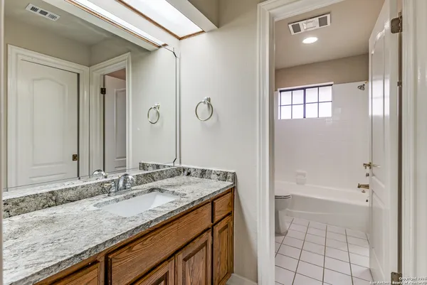 a bathroom with a granite countertop sink a mirror and a bathtub