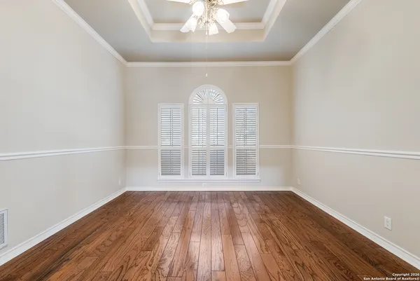 an empty room with wooden floor chandelier and windows