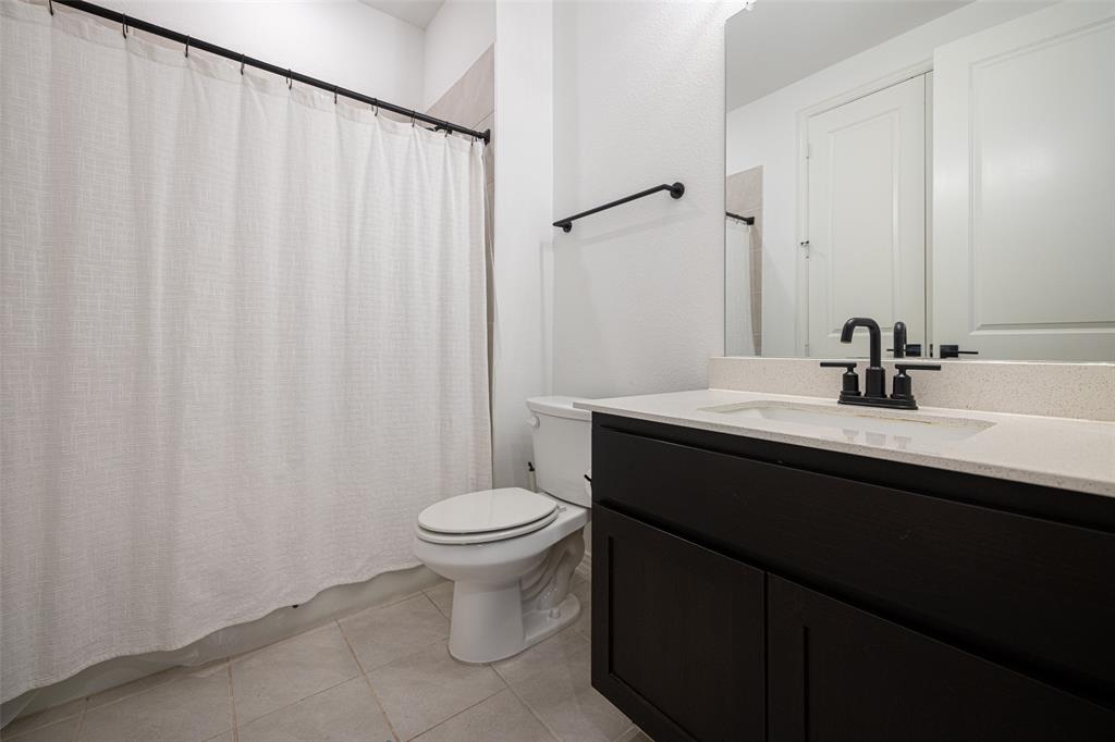 7537 Laburnam Road Dallas, TX 75228 - Photo 5 of 30 Bathroom featuring a dark wood-finish vanity with a light countertop, black fixtures, and tiled flooring