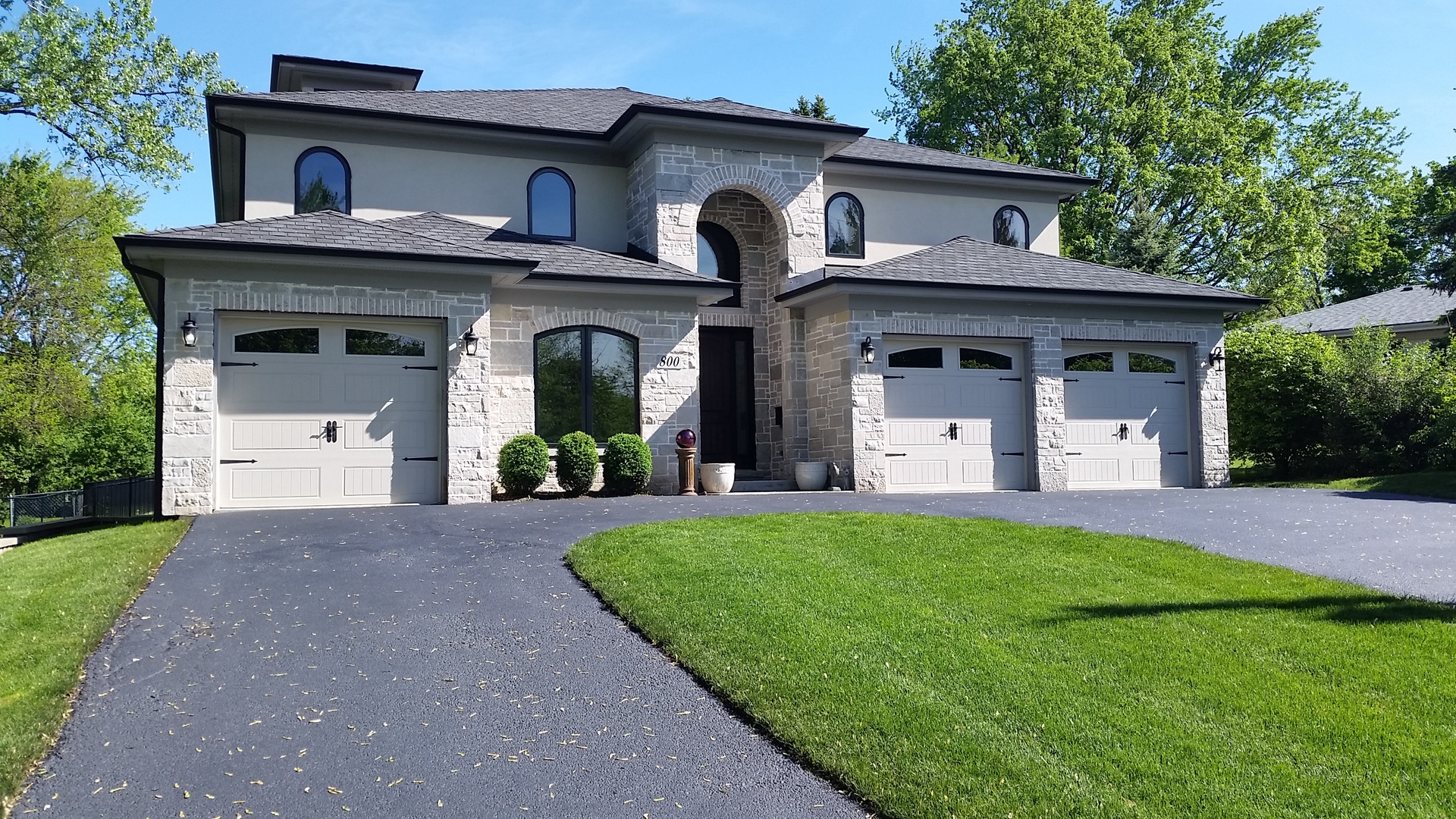 a front view of a house with a garden and trees