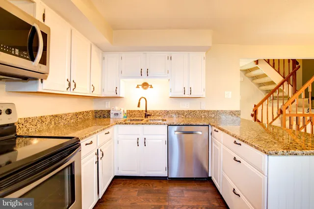 a kitchen with granite countertop white cabinets and white appliances