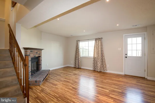 a view of empty room with wooden floor and fireplace