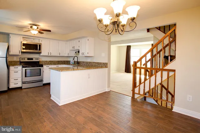 a kitchen with stainless steel appliances granite countertop a sink dishwasher a stove and a dining table with wooden floor