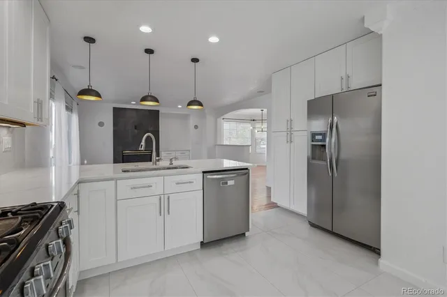 a kitchen with stainless steel appliances granite countertop a refrigerator a sink and a stove