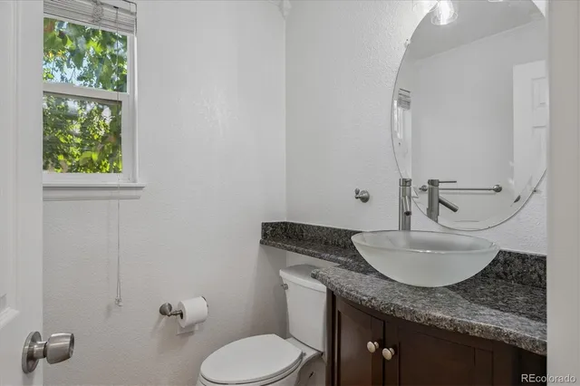 a bathroom with a granite countertop toilet sink and mirror