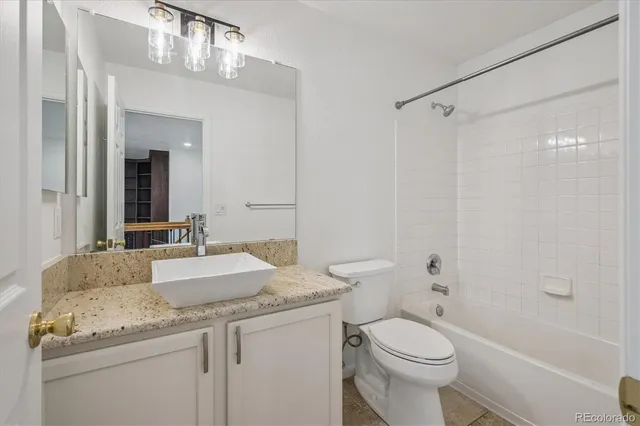 a bathroom with a granite countertop sink toilet mirror and a bathtub