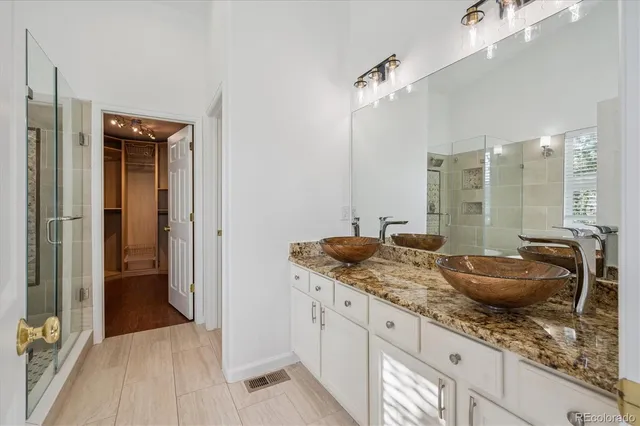 a bathroom with a granite countertop sink a mirror and shower