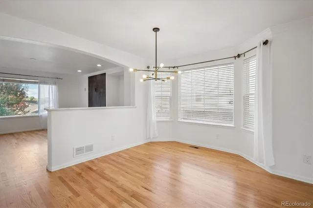 a view of a room with wooden floor chandelier and windows