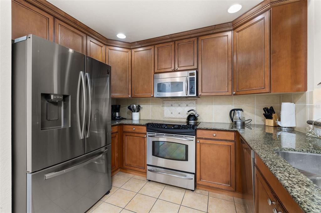 1100 Sunset View Circle, Unit 302 Reunion, FL 34747 - Photo 16 of 56 a kitchen with stainless steel appliances granite countertop a refrigerator stove and sink