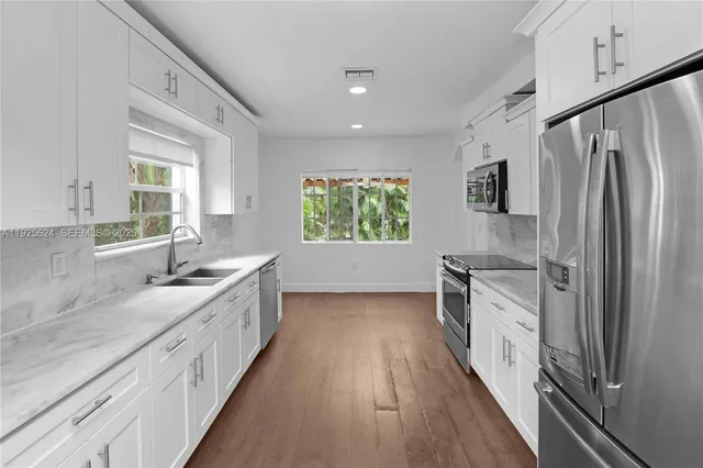 a kitchen with granite countertop a sink stove and refrigerator