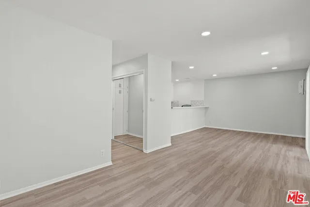 a view of a hallway with wooden floor and a refrigerator
