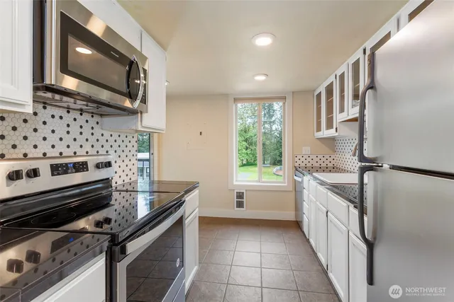 a kitchen with granite countertop a stove sink and microwave