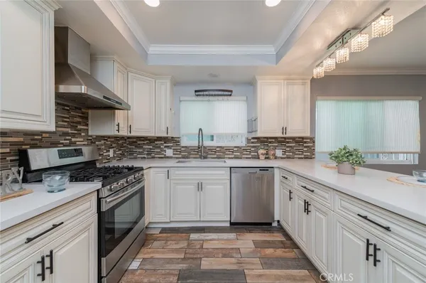 a kitchen with granite countertop white cabinets stainless steel appliances a sink and a counter space