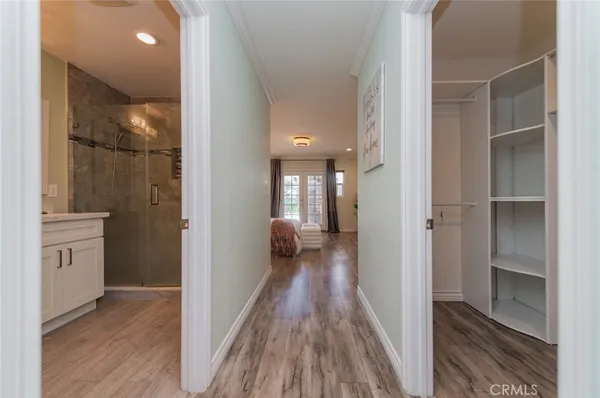 a view of a hallway with wooden floor and a bathroom