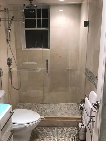 a bathroom with a toilet a sink a shower and a window