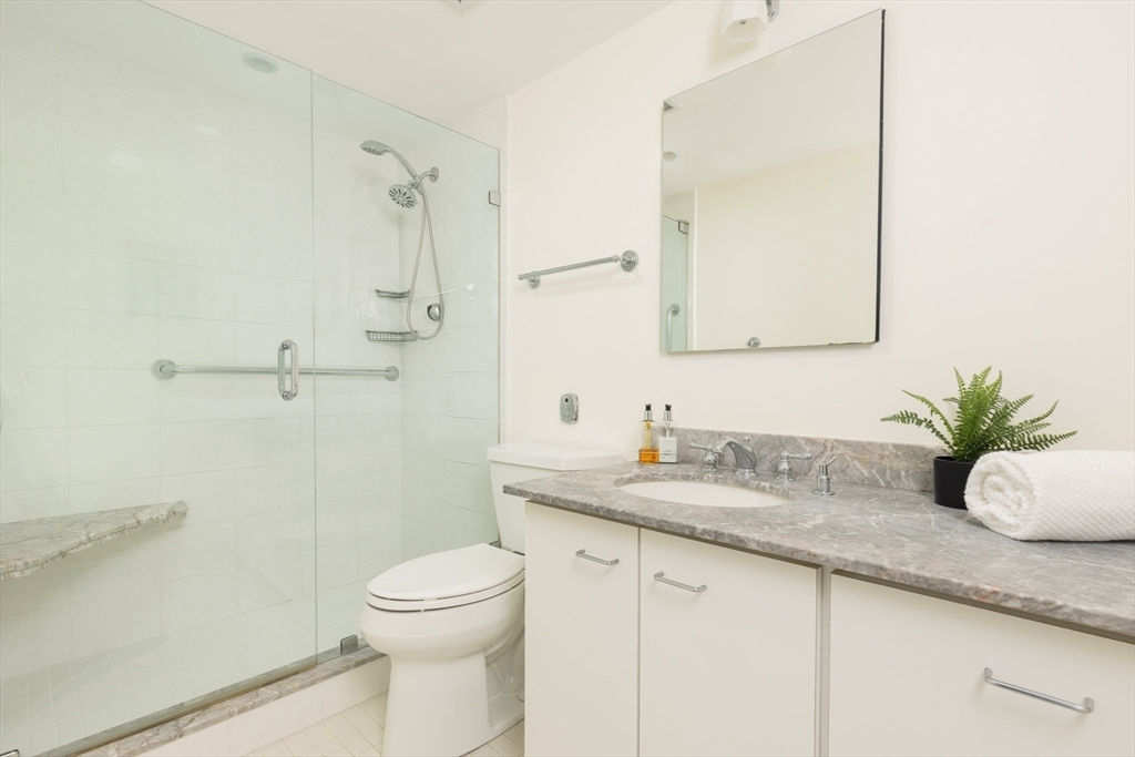 975 Memorial Drive, Unit 209 Cambridge, MA 02138 - Photo 12 of 23 a bathroom with a granite countertop sink a toilet and a mirror