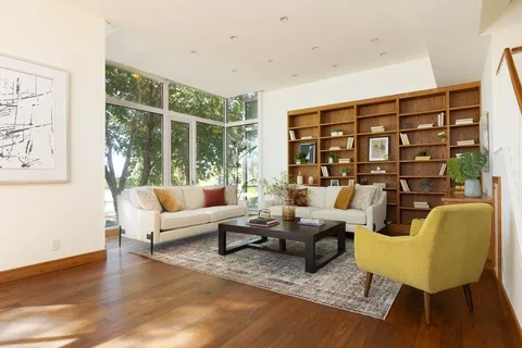 a living room with furniture large window and wooden floor