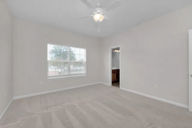 an empty room with windows and a chandelier fan