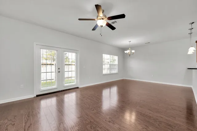 a view of an empty room with a window and wooden floor