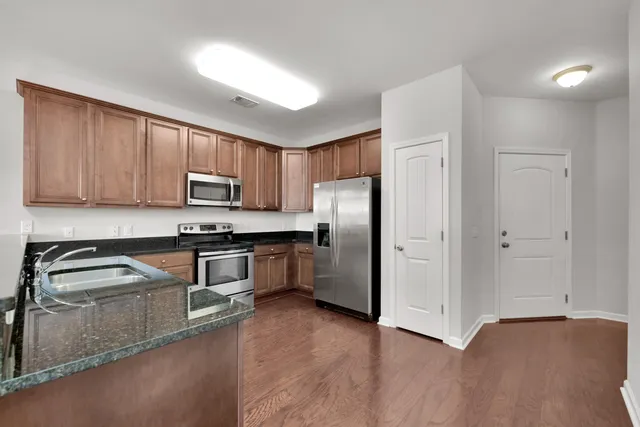 a kitchen with granite countertop a refrigerator and a stove top oven
