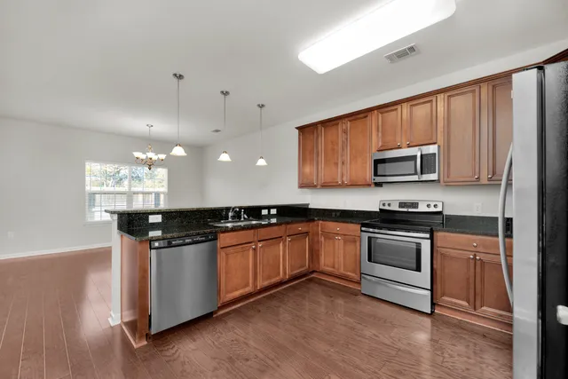 a kitchen with stainless steel appliances granite countertop a stove a sink dishwasher and a microwave oven with wooden floor