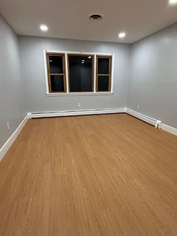 an empty room with wooden floor and mirror