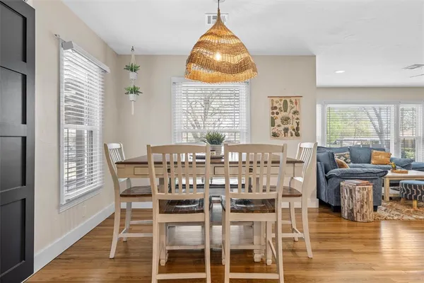 a dining room with wooden floor a chandelier a glass table and chairs