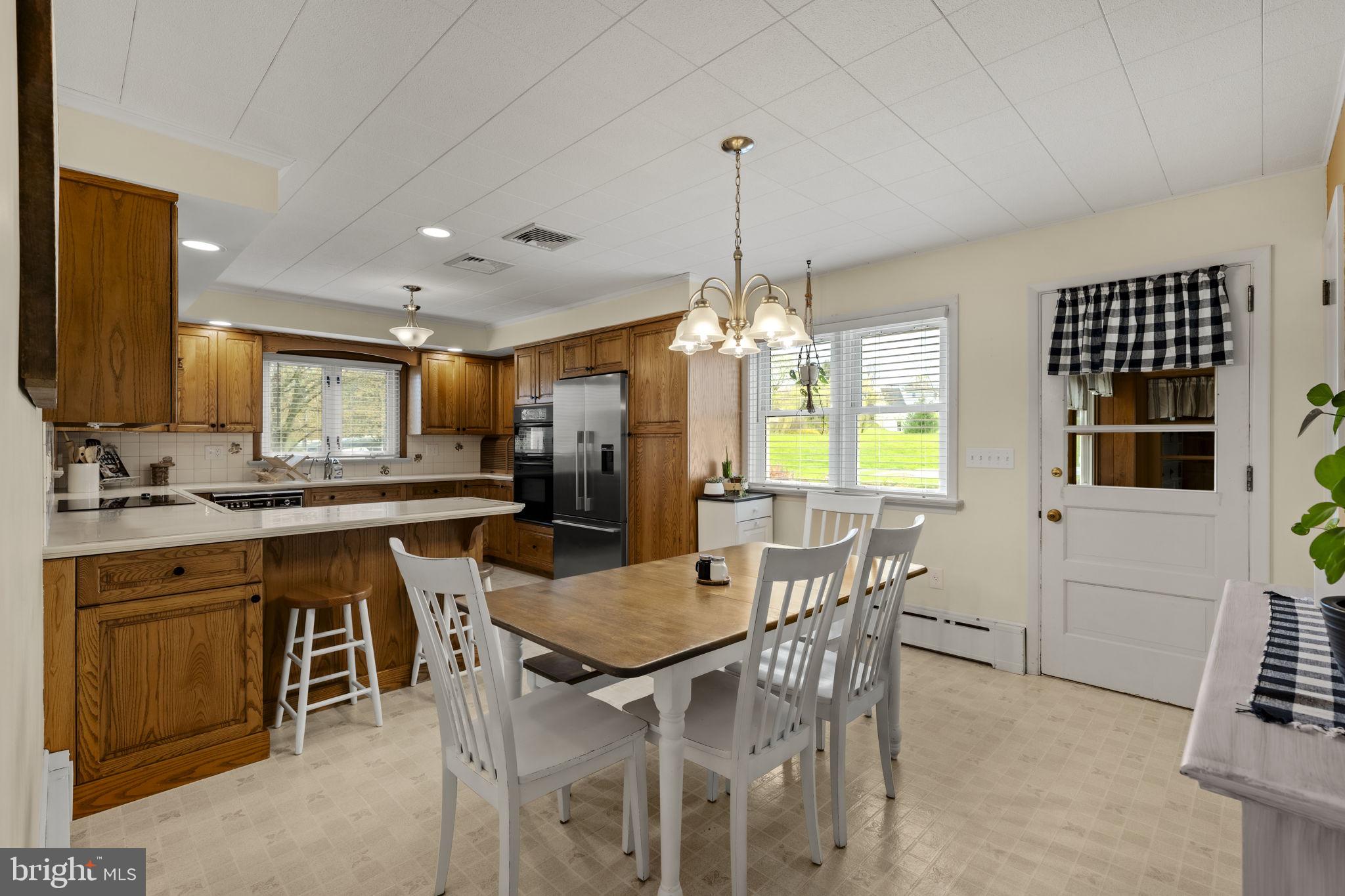 218 Lauschtown Road Denver, PA 17517 - Photo 26 of 78 a kitchen with stainless steel appliances granite countertop a stove top oven a sink a dining table and chairs with wooden floor