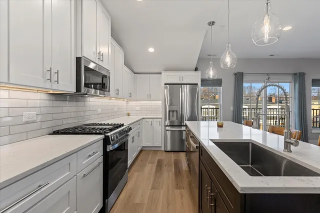 a kitchen with stainless steel appliances granite countertop a sink a stove and a refrigerator