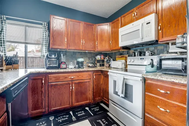 a kitchen with stainless steel appliances granite countertop a stove a sink and a microwave