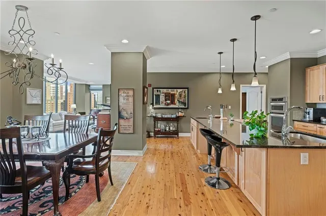 a kitchen with stainless steel appliances granite countertop a stove top oven a sink a dining table and chairs with wooden floor