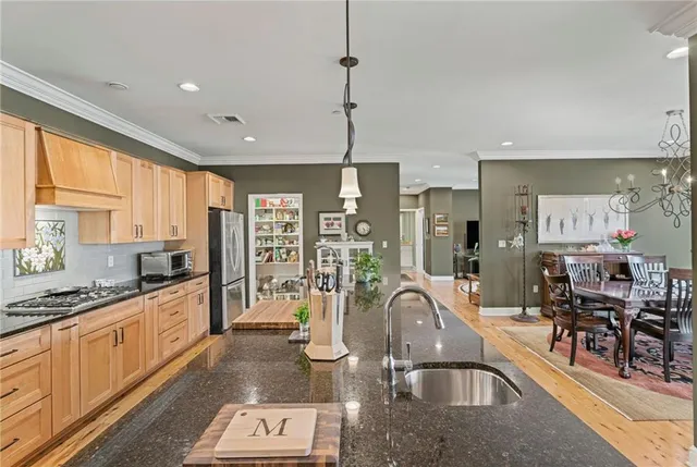 a kitchen with stainless steel appliances granite countertop wooden floor window and chairs