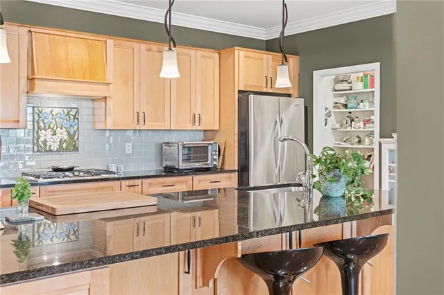 a kitchen with kitchen island a counter top space a sink a refrigerator and wooden floor
